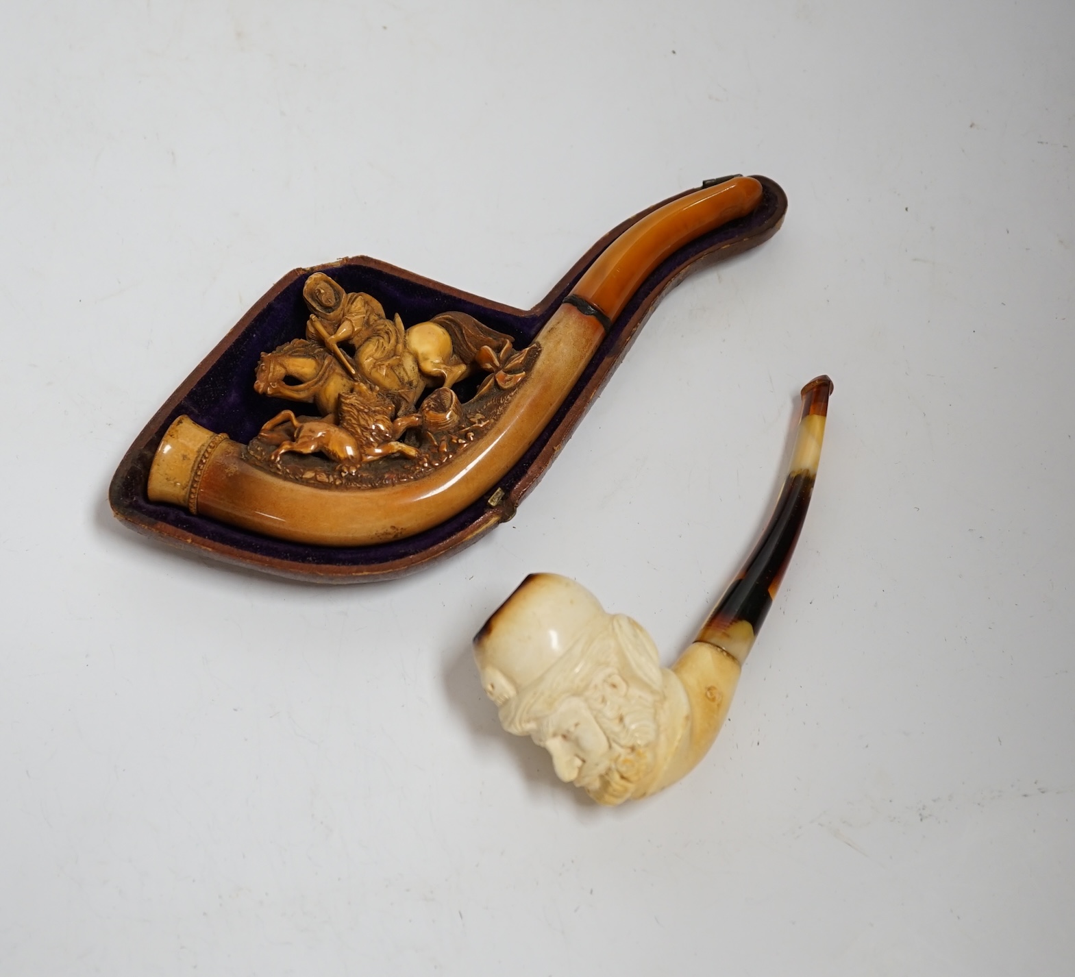 Two carved Meerschaum pipes, one in the form of a huntsman on horseback with amber mouthpiece